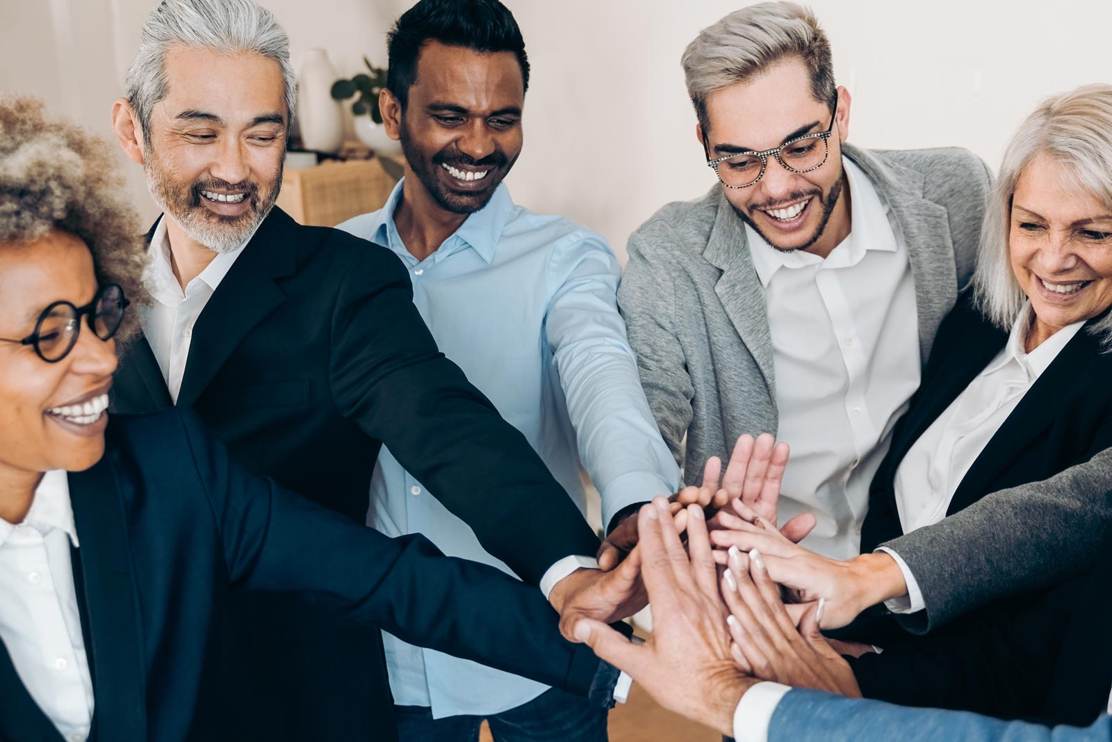Smiling team members huddling and doing a hand-stack